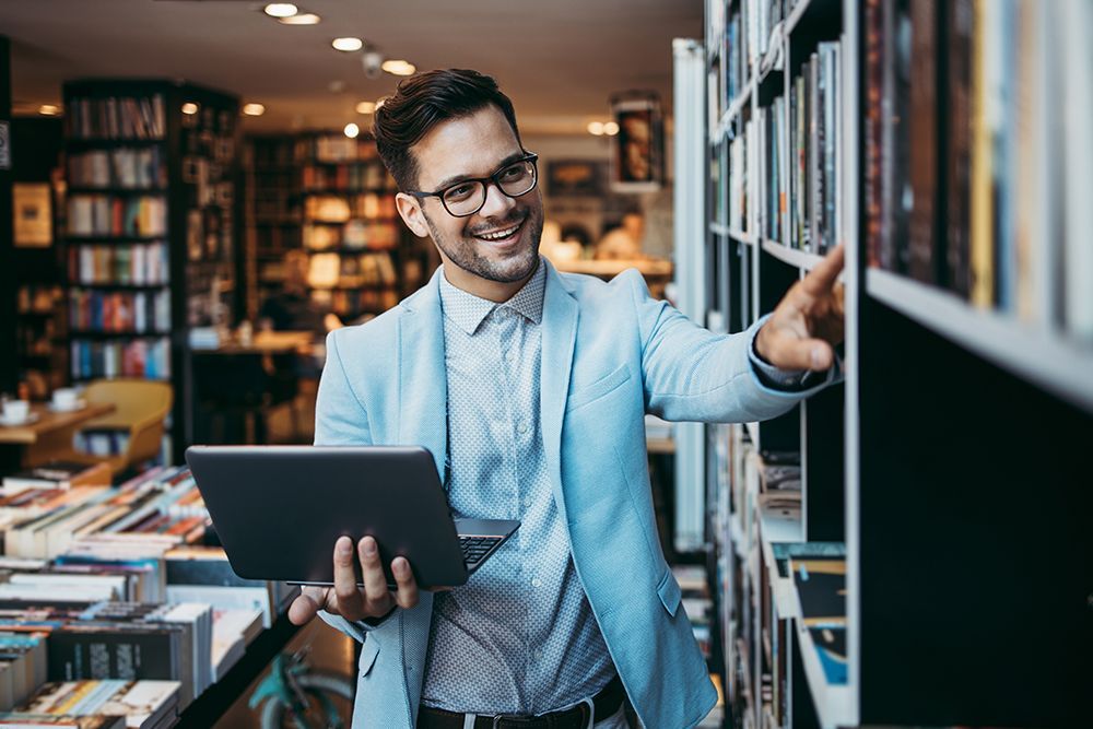 a man in a suit is holding a tablet in a library
