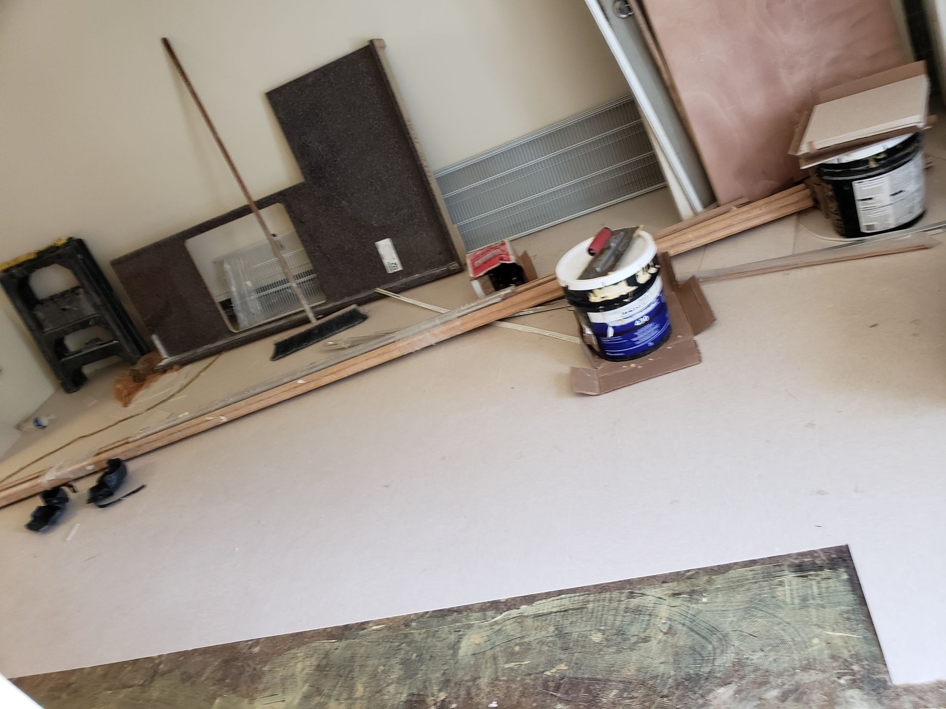 A bucket of paint is sitting on the floor in a room.