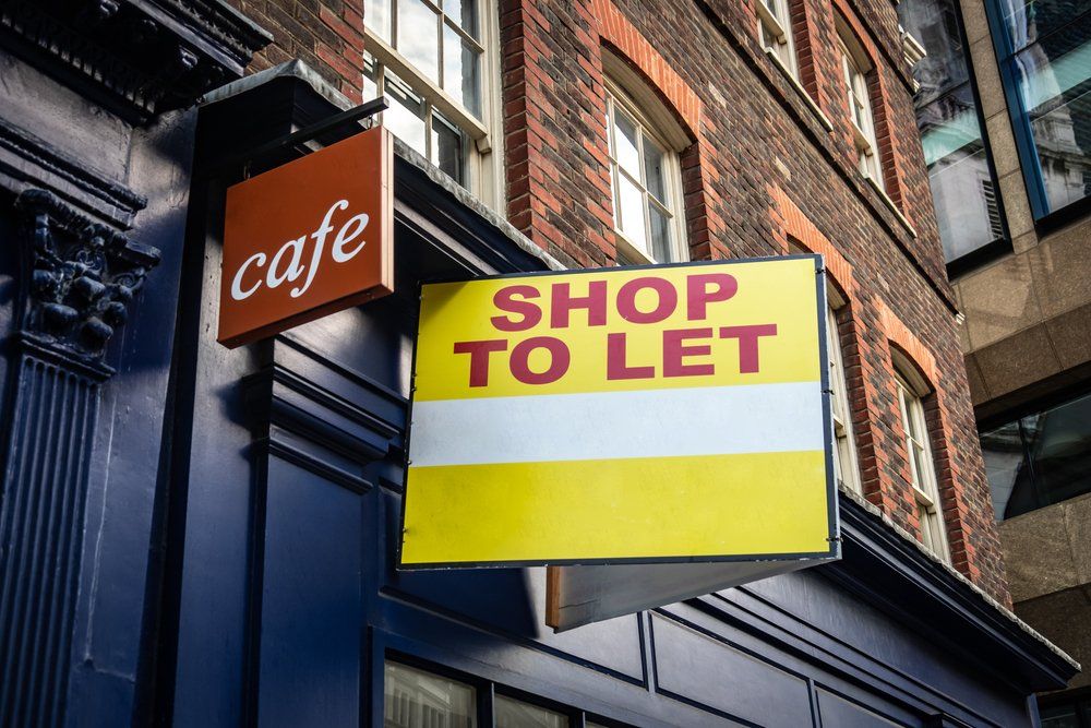 A shop to let sign is hanging on the side of a building.