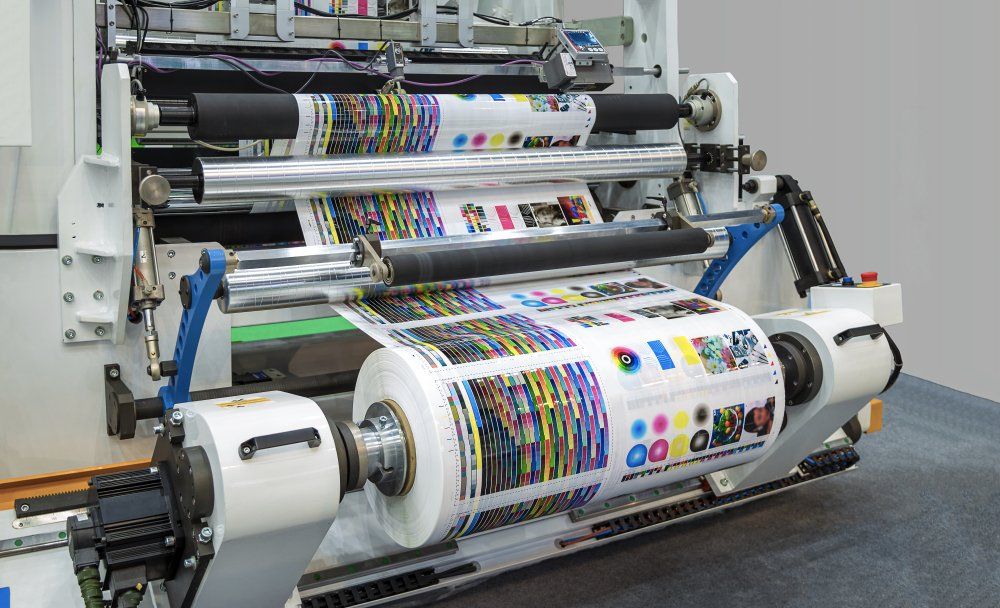 Large industrial printing machine with colorful printed paper rolls.