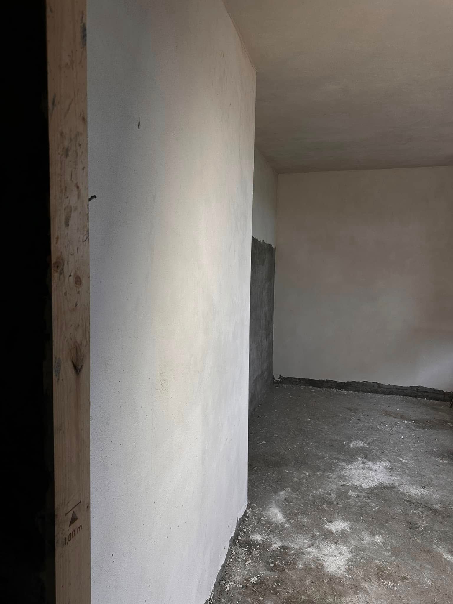 Una stanza vuota con un muro bianco e un pilastro di legno.