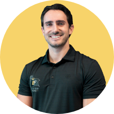 Smiling man in a black polo shirt standing in front of a yellow background