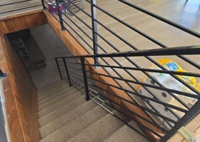 A set of stairs with a metal railing and a stack of toilet paper.