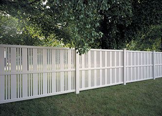A white fence surrounds a lush green yard with trees in the background.