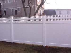 A white vinyl fence is in front of a house.