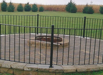 A fence surrounds a fire pit in the middle of a field