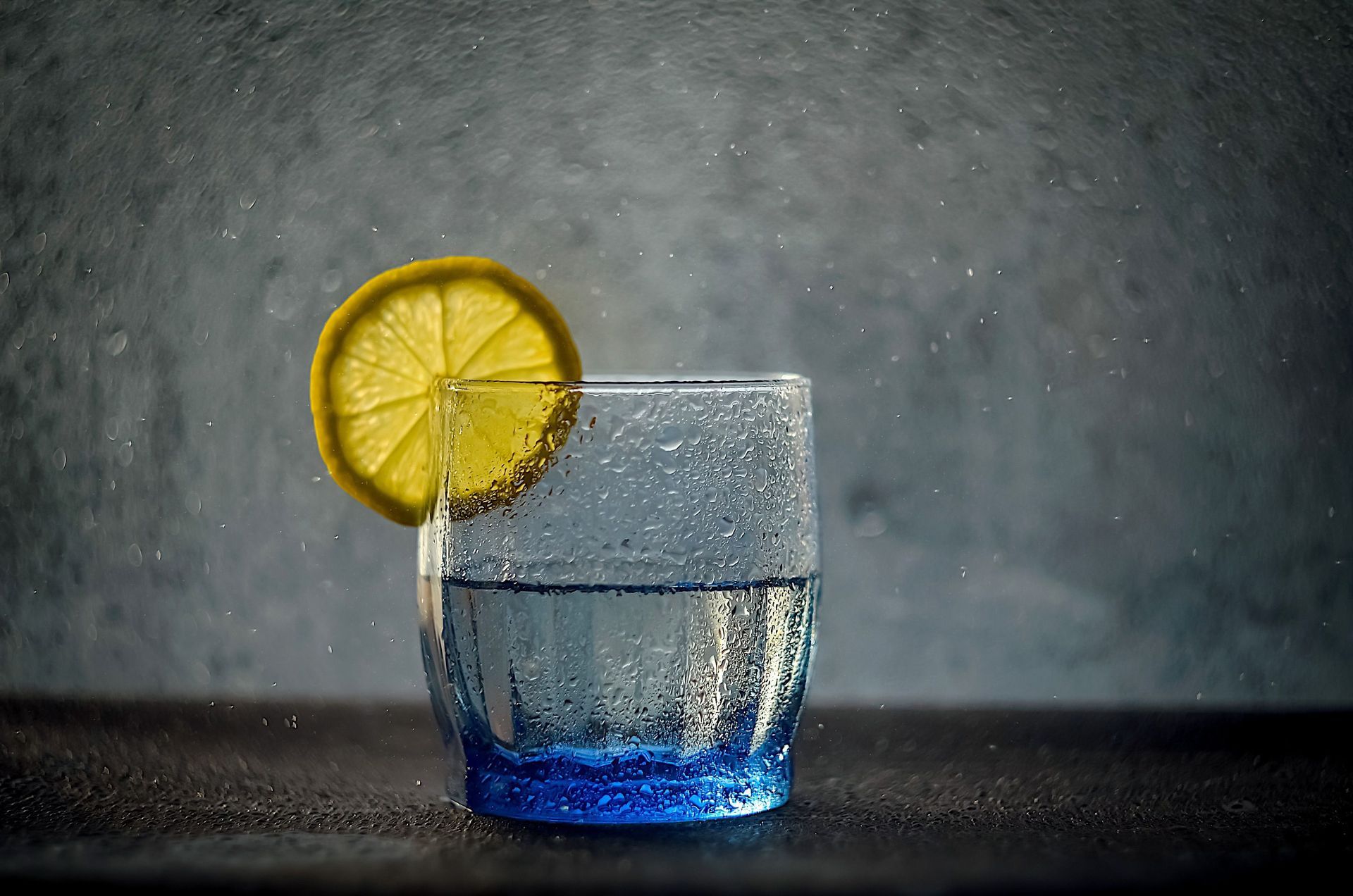 Glass of cold water with a lemon wedge slice.