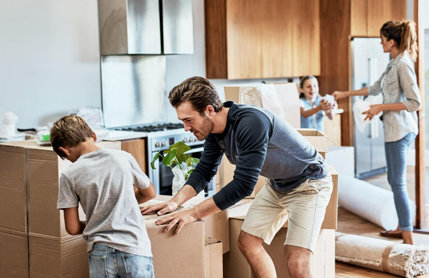 Family unpacking moving boxes in a bright living room
