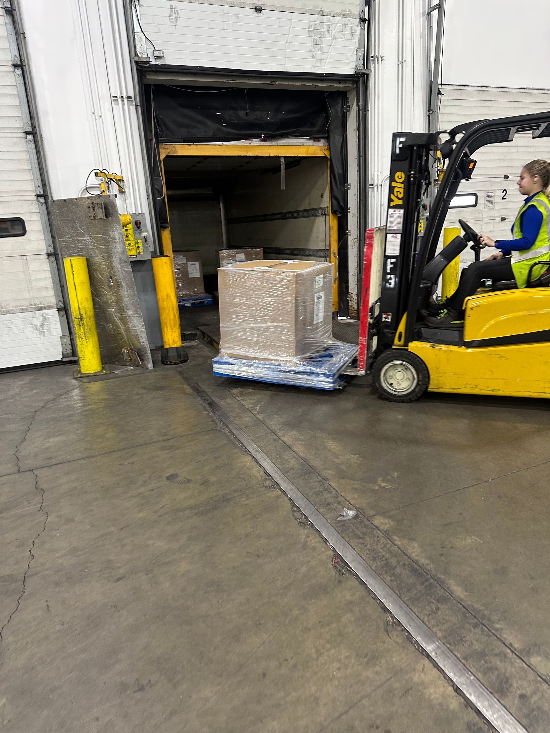 Forklift loading a pallet of boxes into a warehouse truck dock