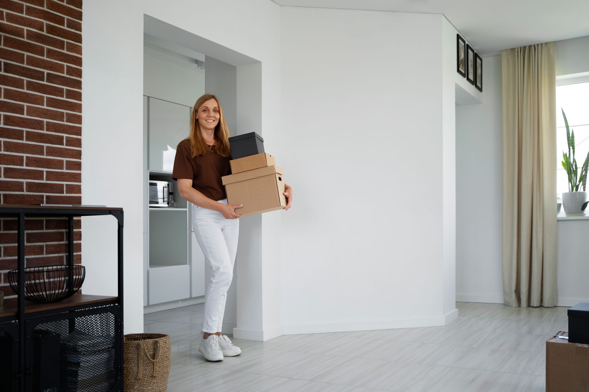 A woman is holding a cardboard box in a living room.