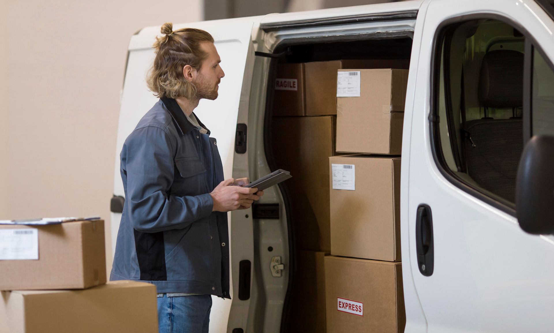 A delivery man is standing next to a van filled with boxes.