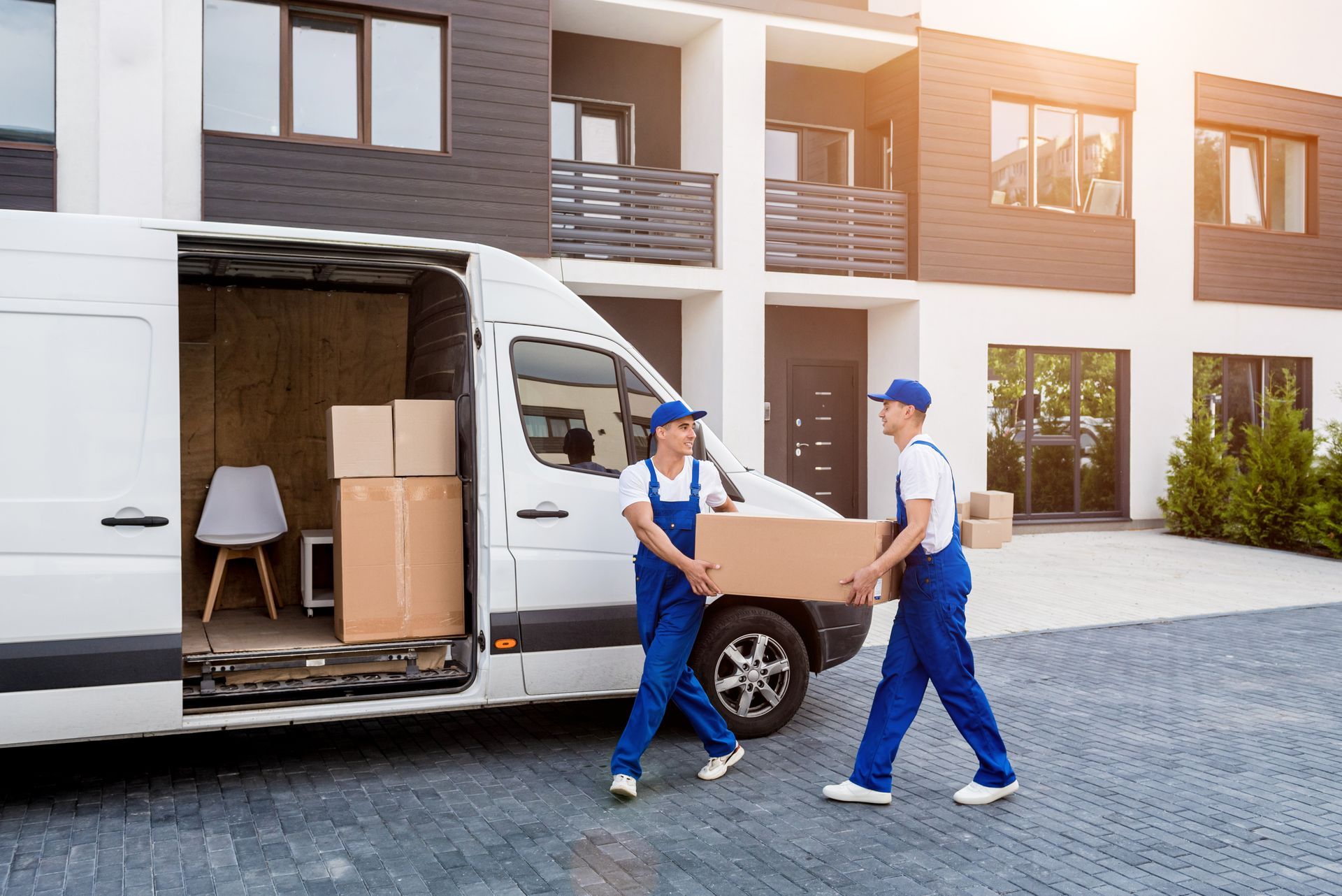 Two men are loading boxes into a van in front of a building.