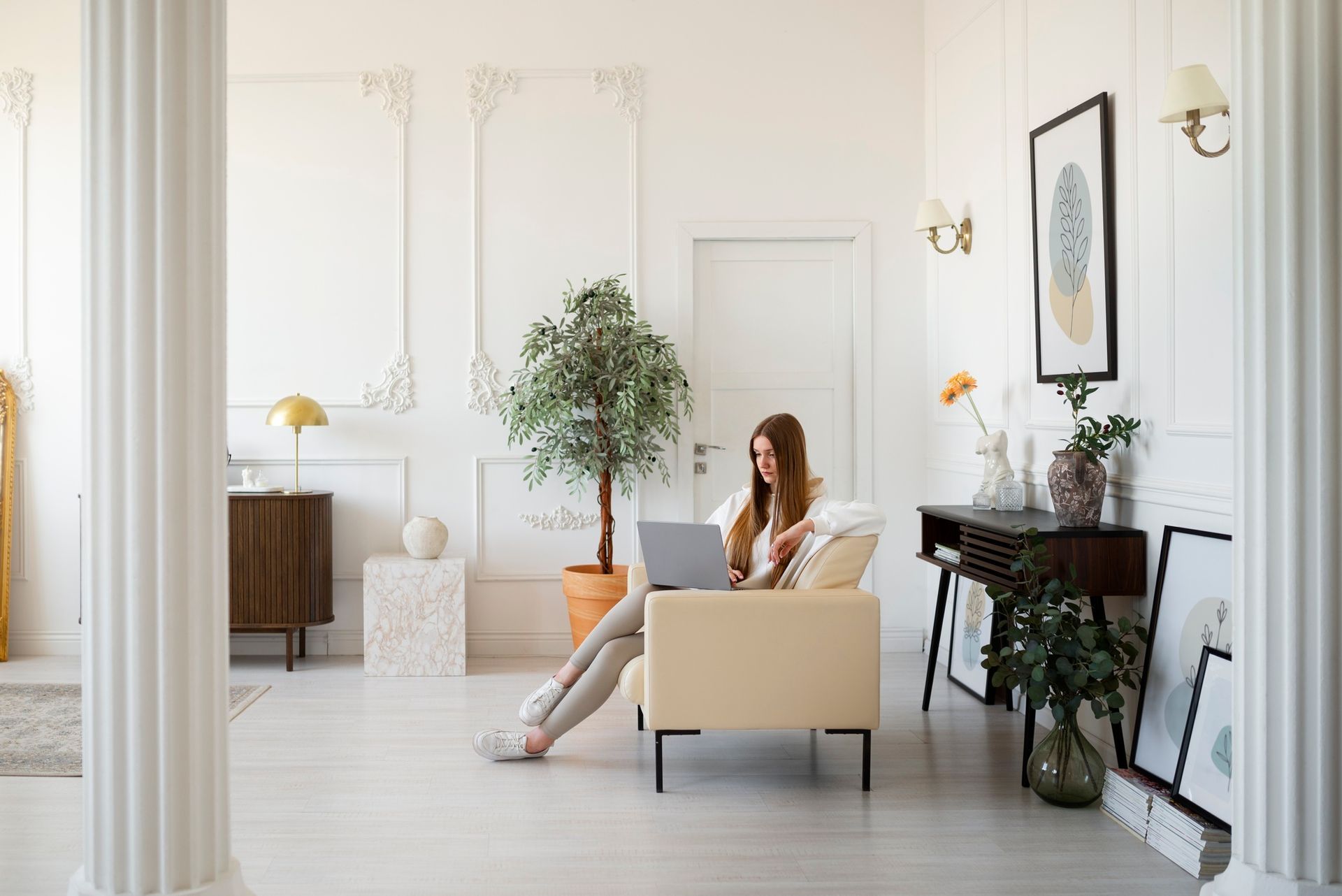 A woman is sitting on a couch in a living room using a laptop computer.