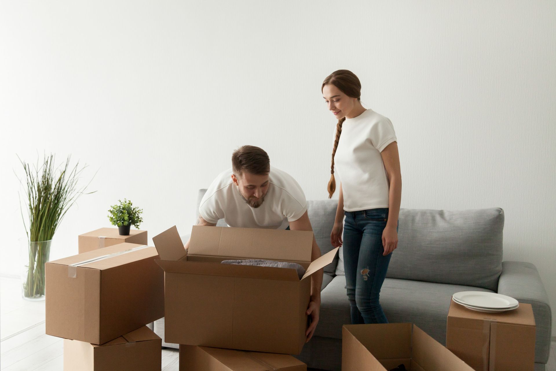A man and a woman are opening boxes in a living room.