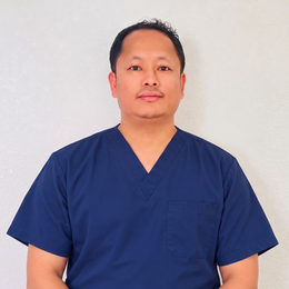 Person in navy blue scrubs standing against a plain white background, facing forward.