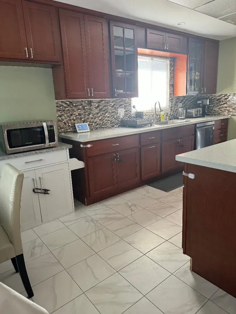 Bright kitchen with dark wood cabinets, white tile floor, central island, and window over the sink.