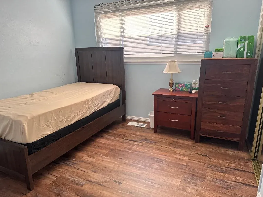 Small bedroom with a bed, dresser, nightstand, and window with blinds.