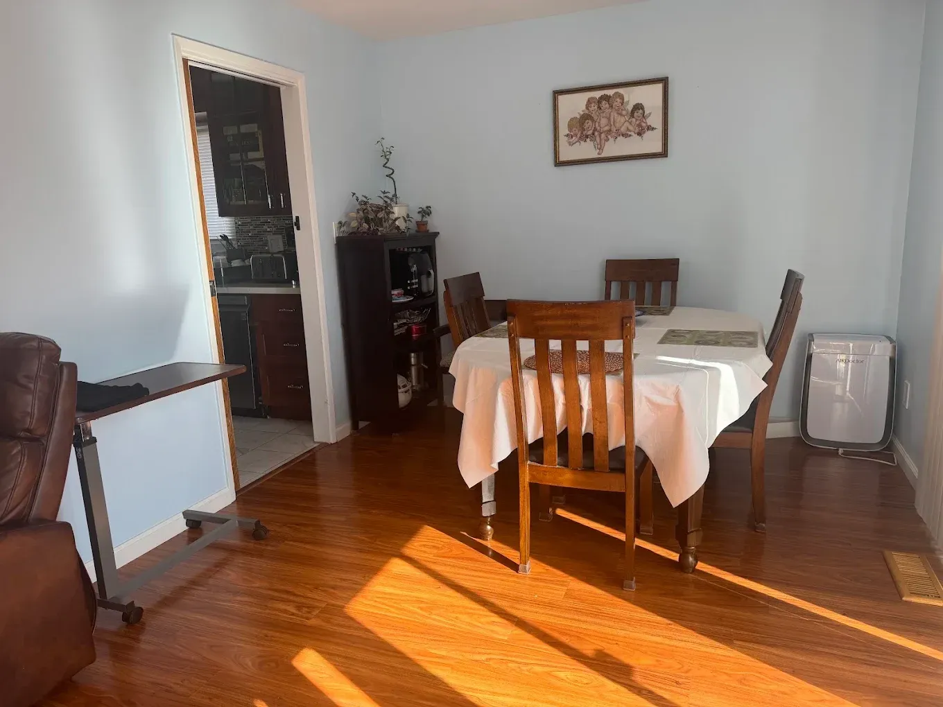 Dining room with wooden chairs, table, and sunlight streaming across a polished floor.