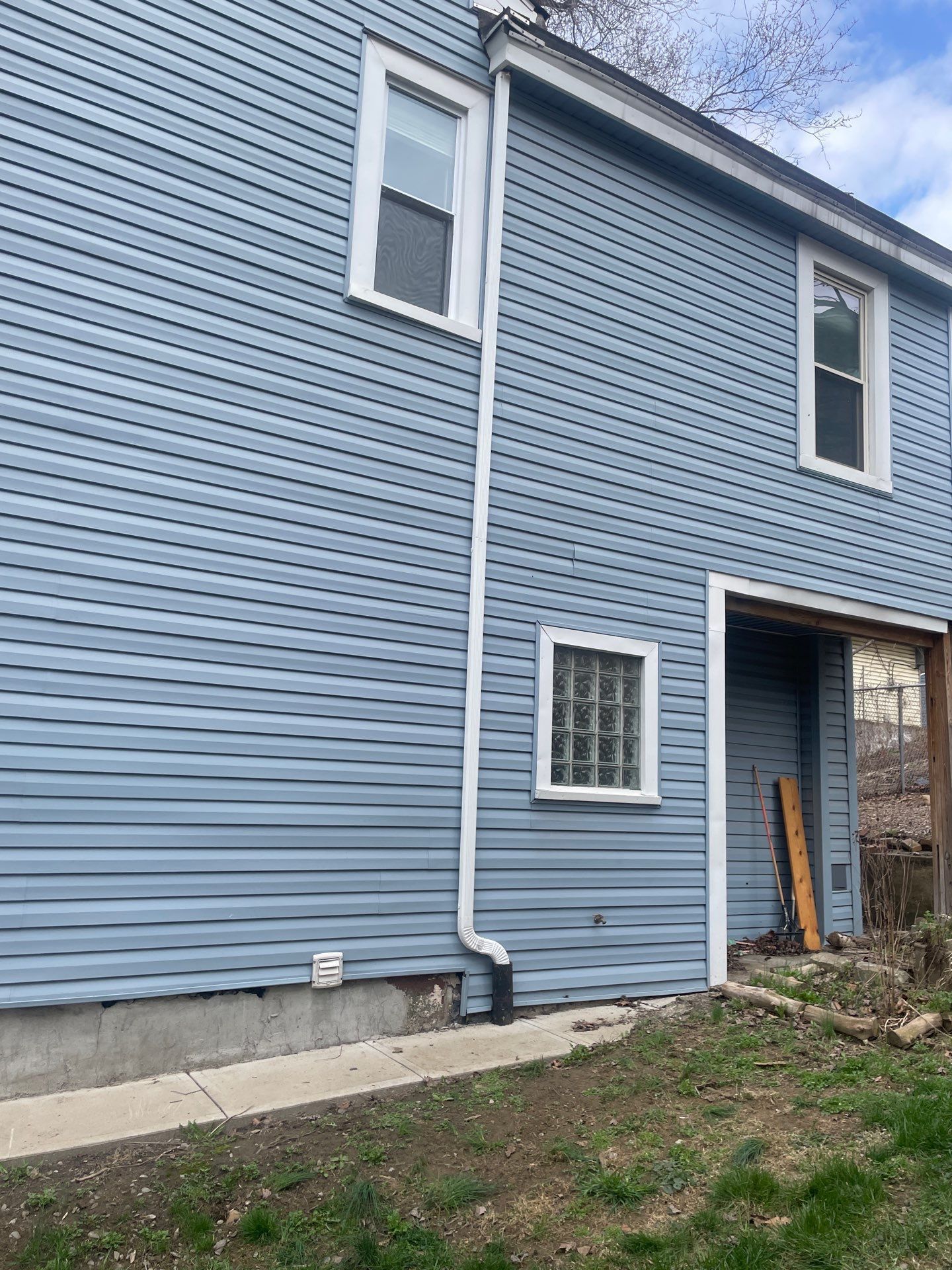 Blue house exterior with white-trimmed windows and an open doorway.