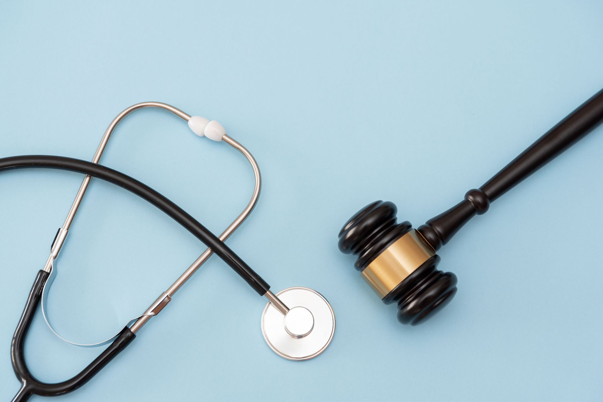 Gavel and stethoscope on a blue background representing healthcare and legal issues.