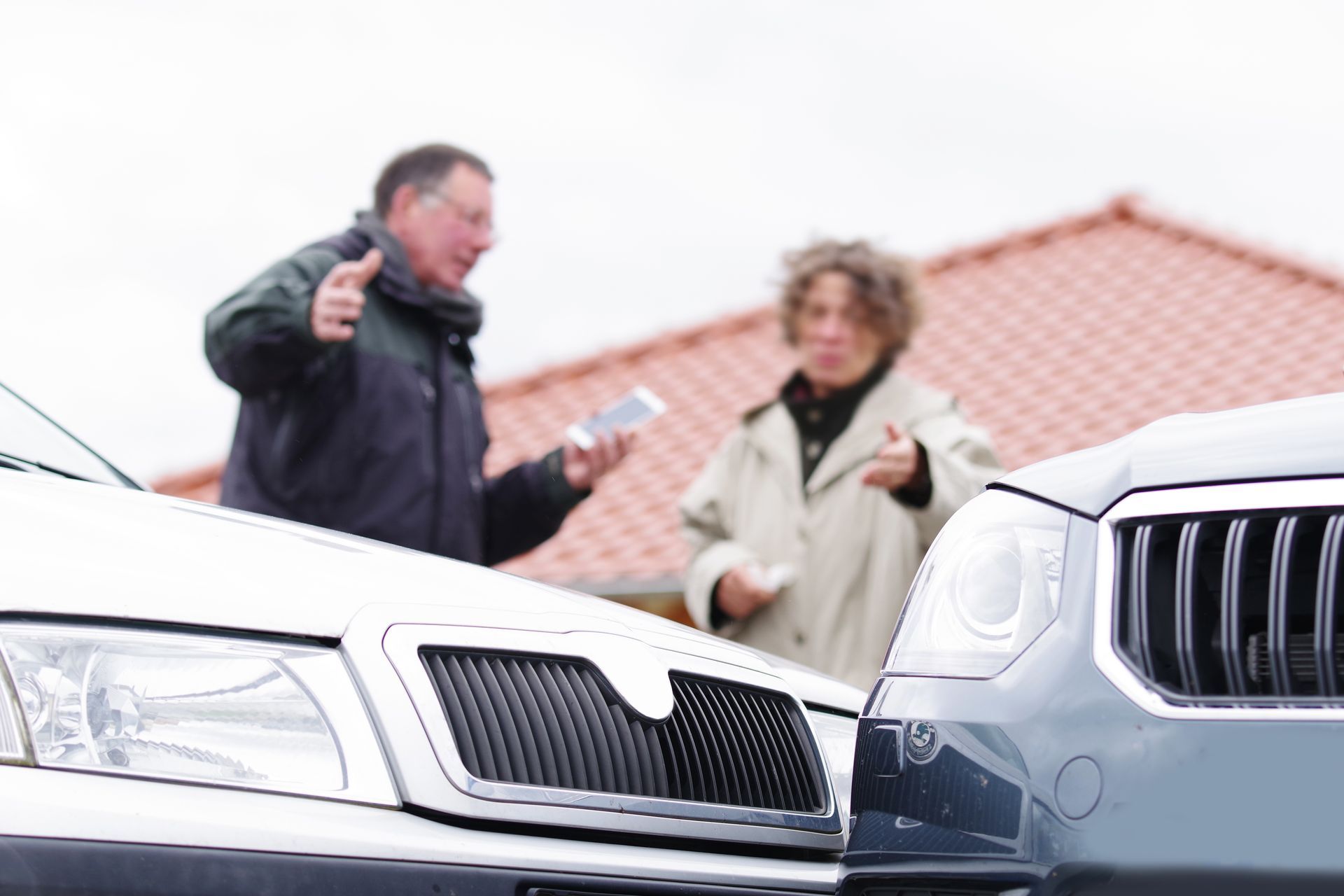 A man and woman stand beside a collision of their cars, engaged in conversation. A man and woman stand beside a collision of their cars, engaged in conversation.