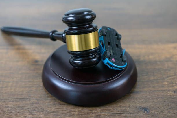 Car accident attorney concept with judge gavel and toy car on wooden table surface.