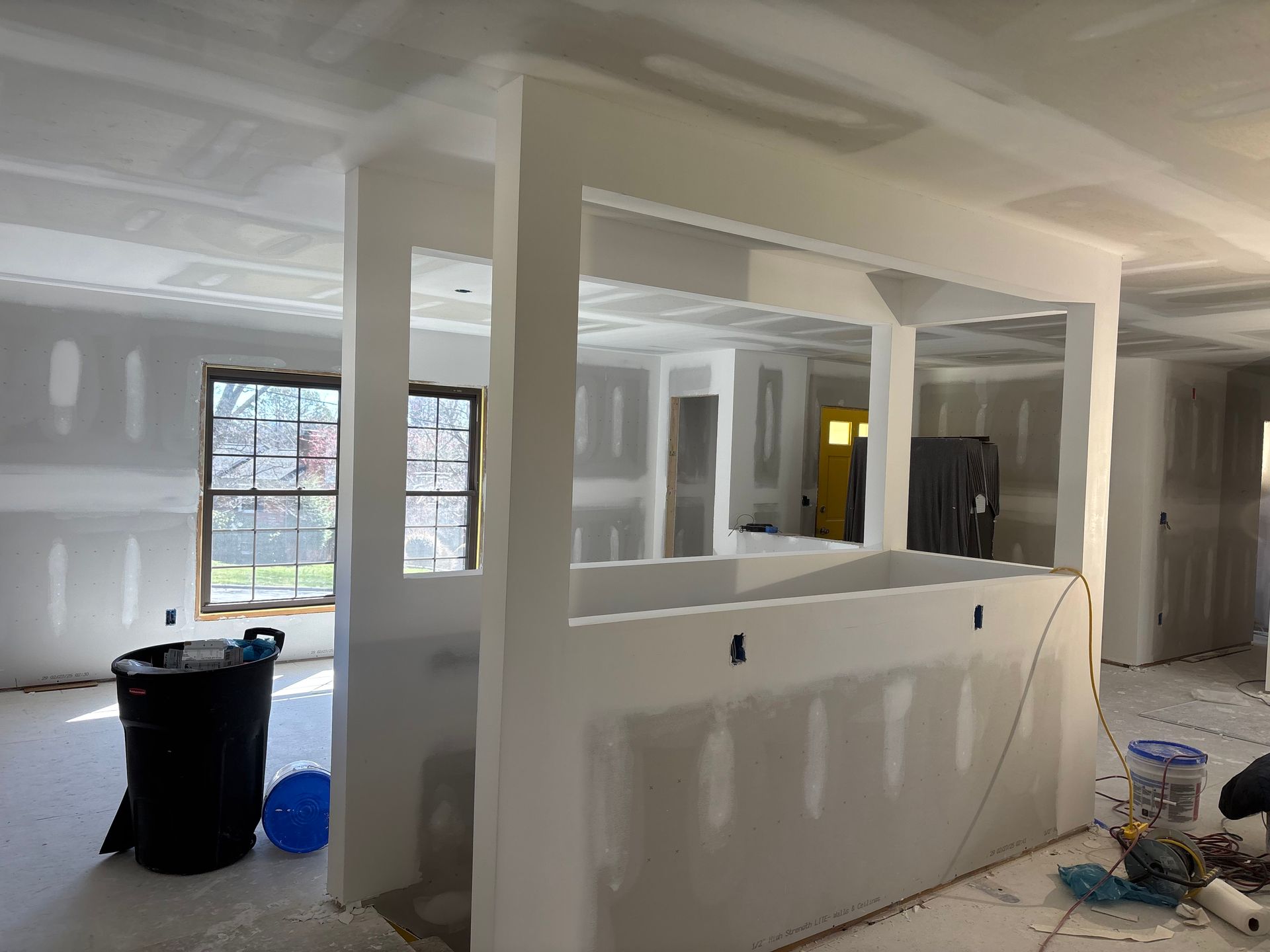 Partially finished room with white drywall, window, and construction materials on the floor