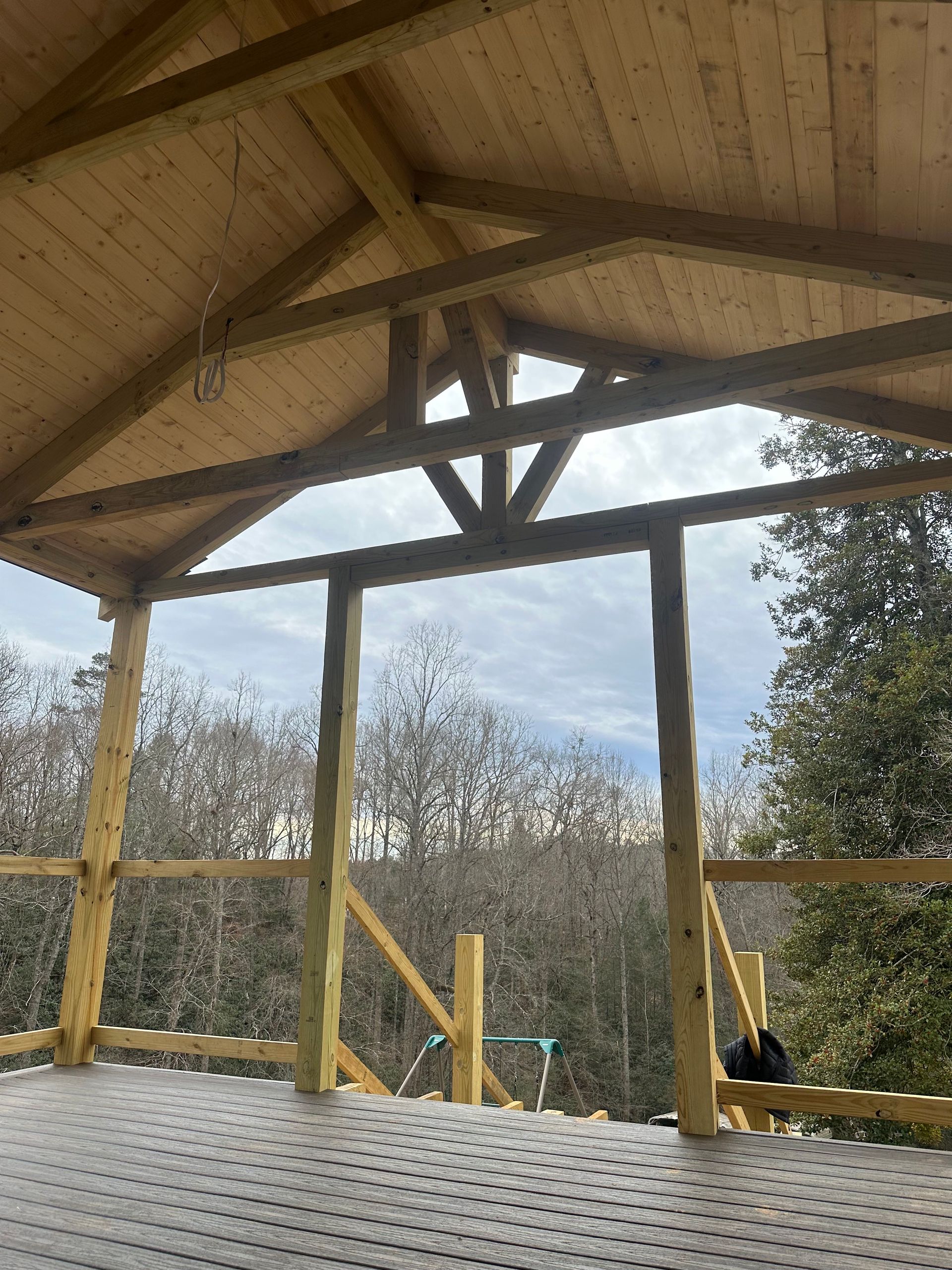 Wooden pavilion with a peaked roof, overlooking trees and a snowy ground