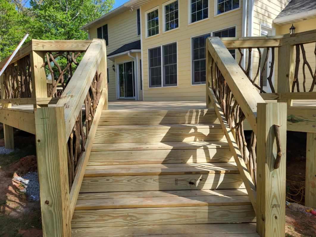 Wooden ramp leading to a beige house with large windows and railings