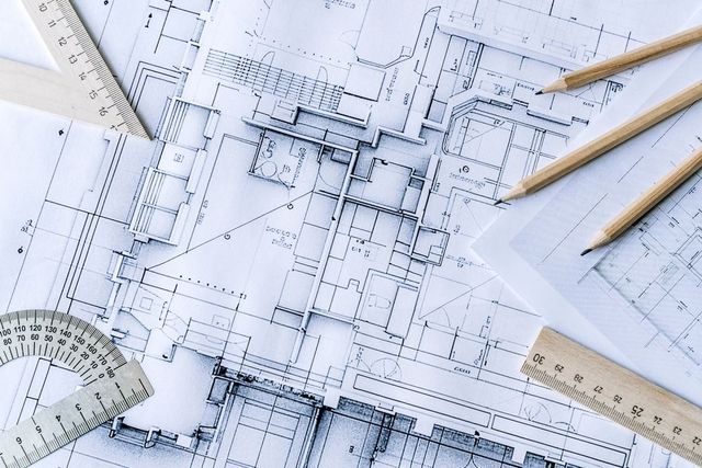 Blueprint of an architectural floor plan with pencils and ruler on top