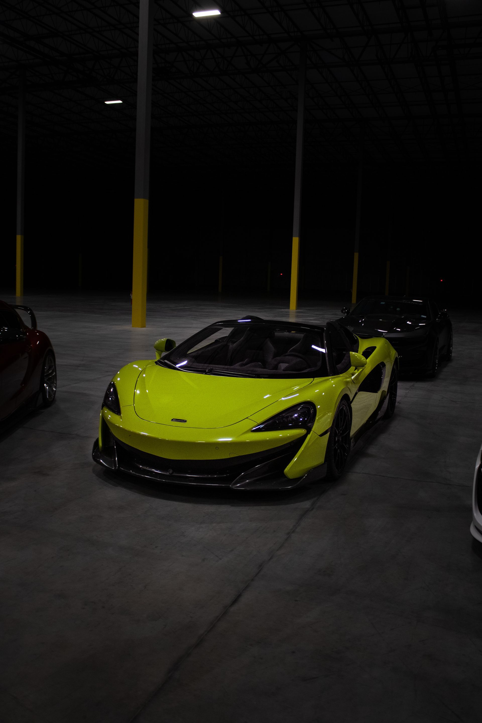 Bright yellow sports car parked in a dim garage at night