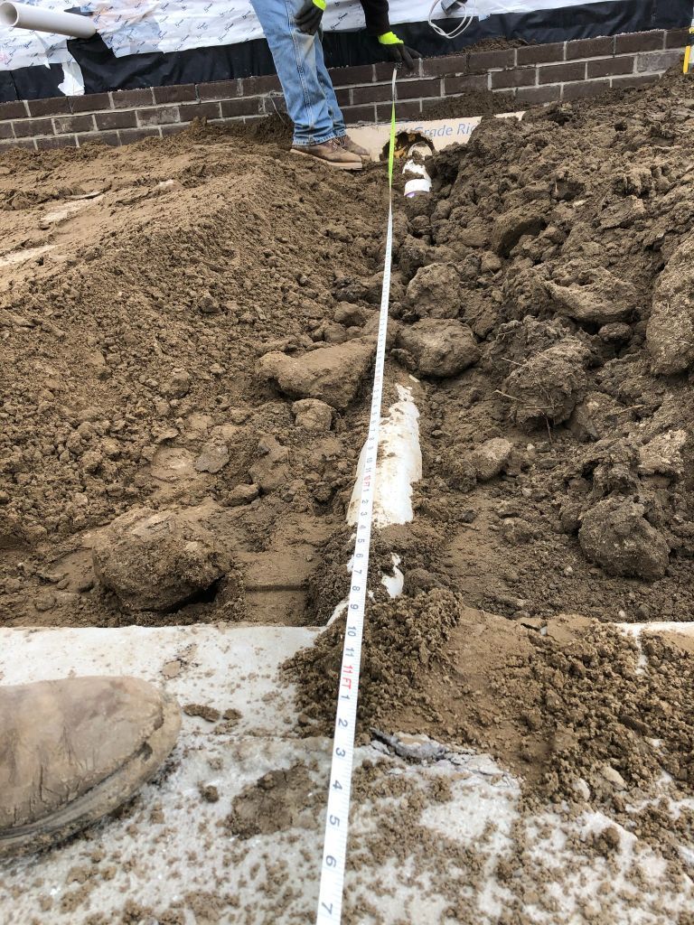 Rough dirt trench with a measuring tape stretched along the center on a construction site