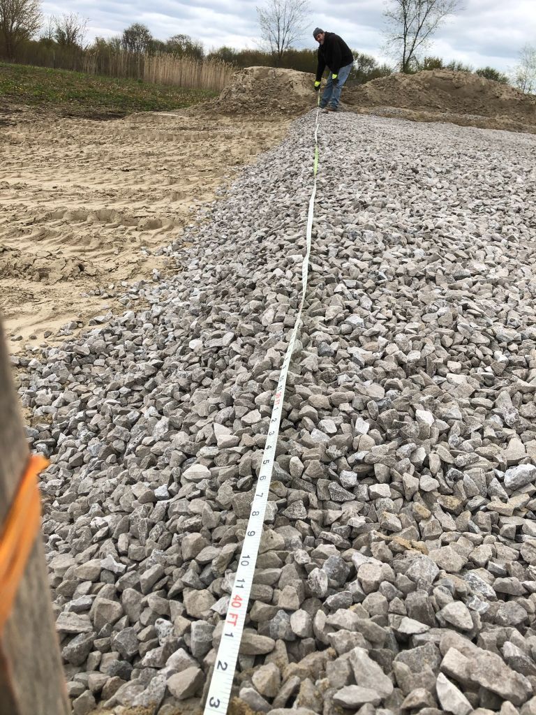 Worker leveling gravel with a measuring tape on a construction site