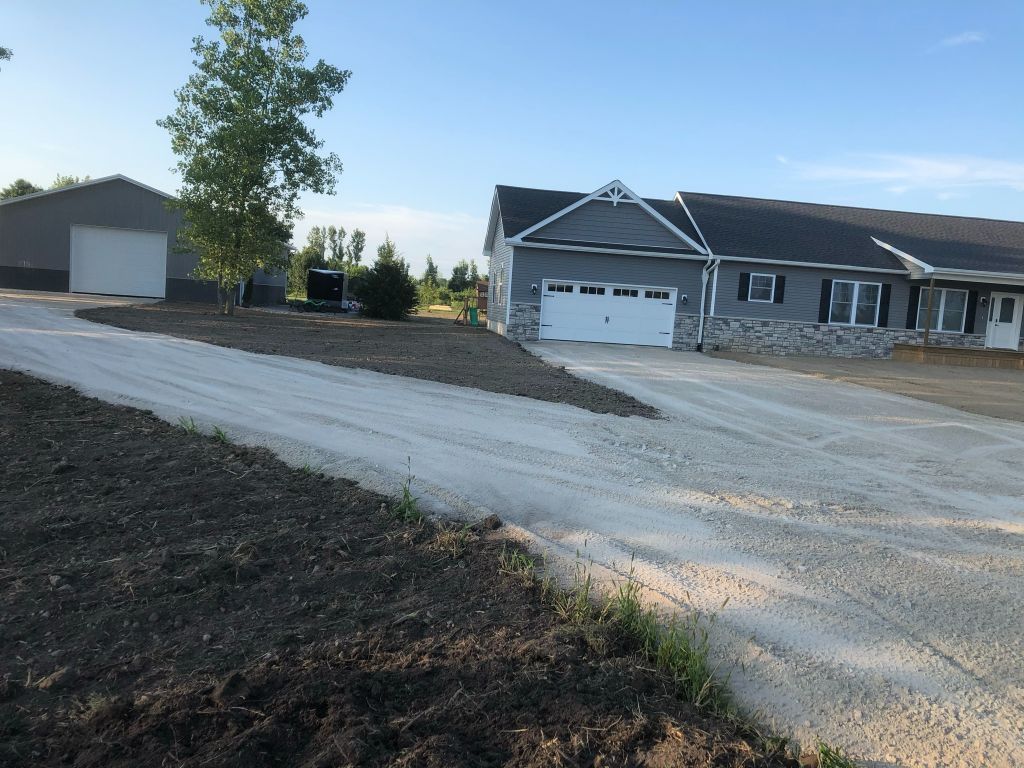 Gravel driveway and newly built homes on a sunny suburban lot with a detached garage