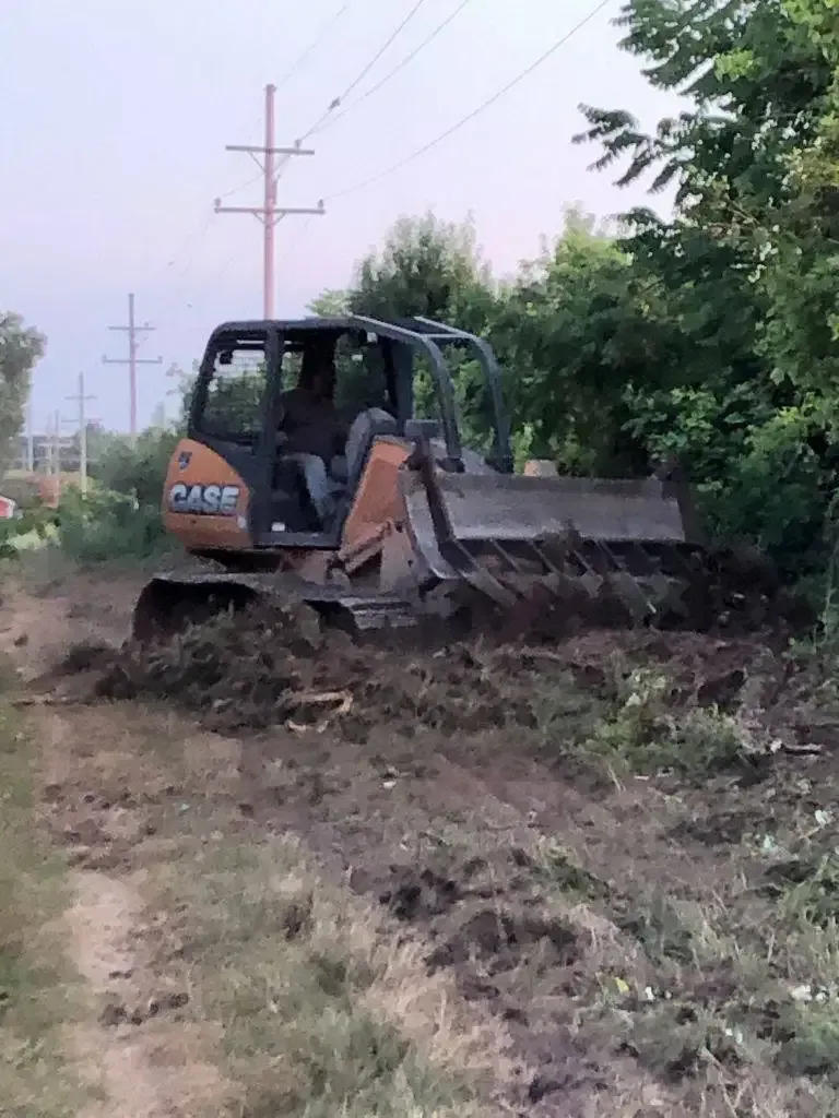 Yellow excavator digging soil beside a house under construction on a sunny day