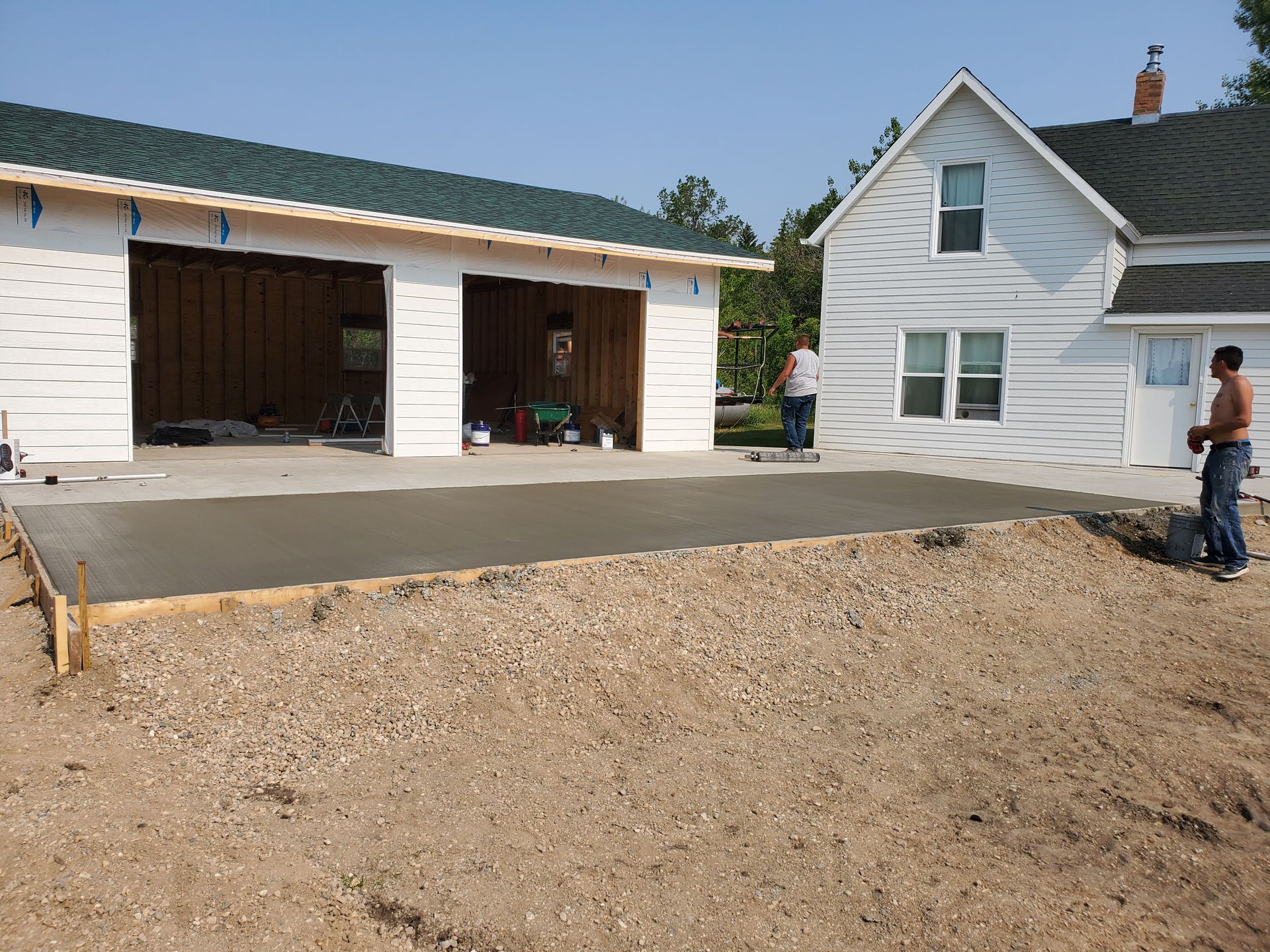 New driveway beside an open garage and white house, with a person standing at the right edge.
