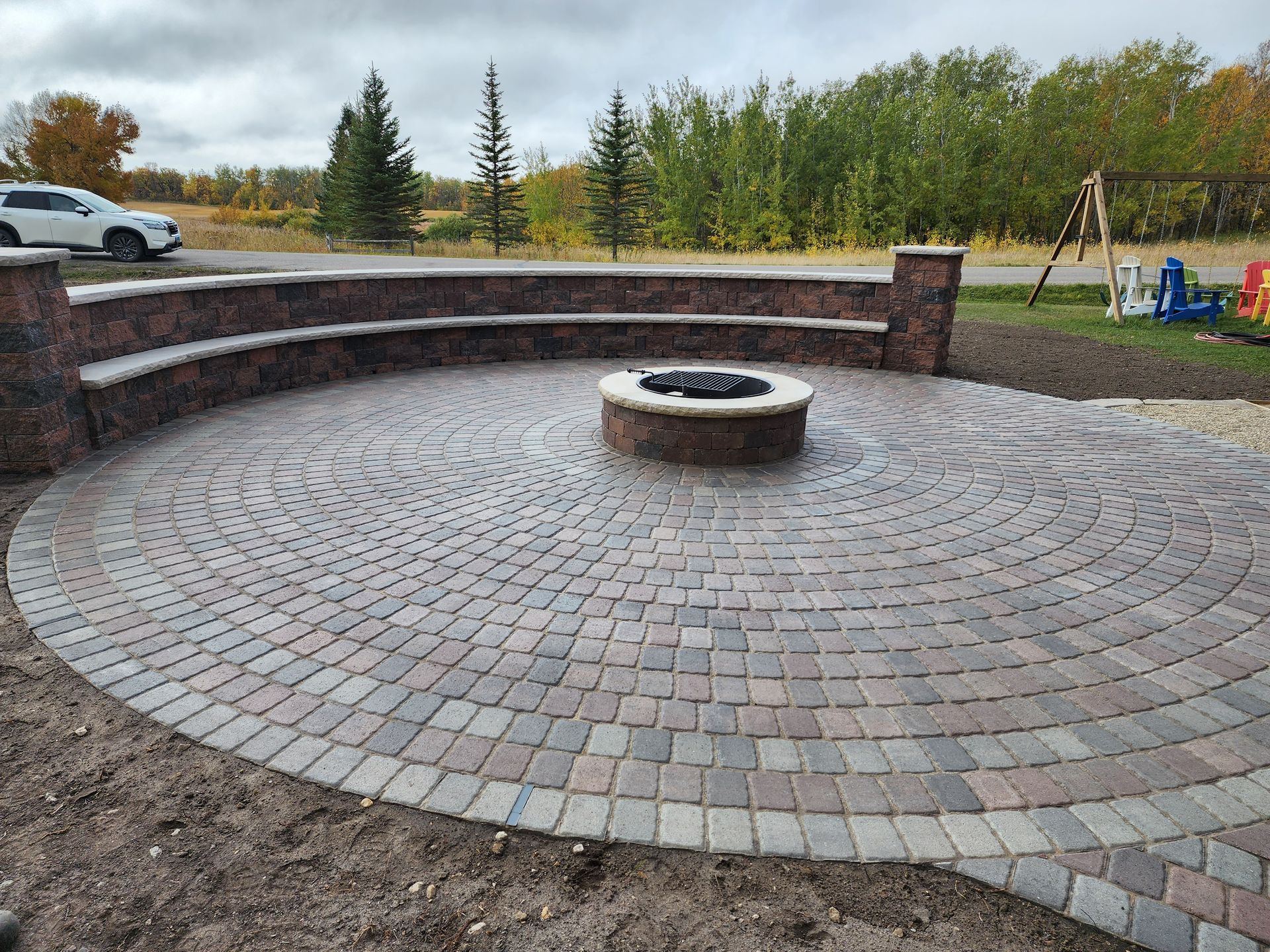 Circular brick fire pit with curved seating wall in an outdoor park setting