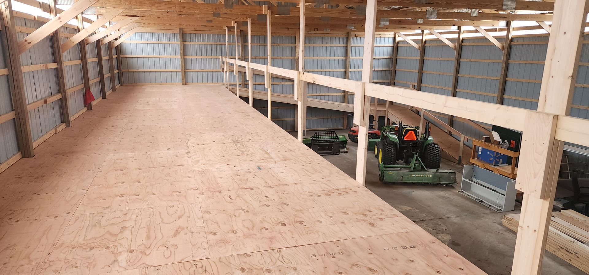 Empty wooden loft in a barn with tractors parked below