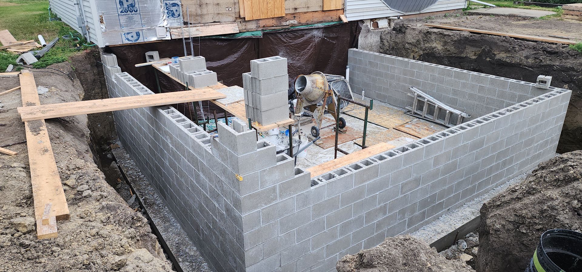 Partially built brick foundation with wooden supports and concrete posts at a construction site