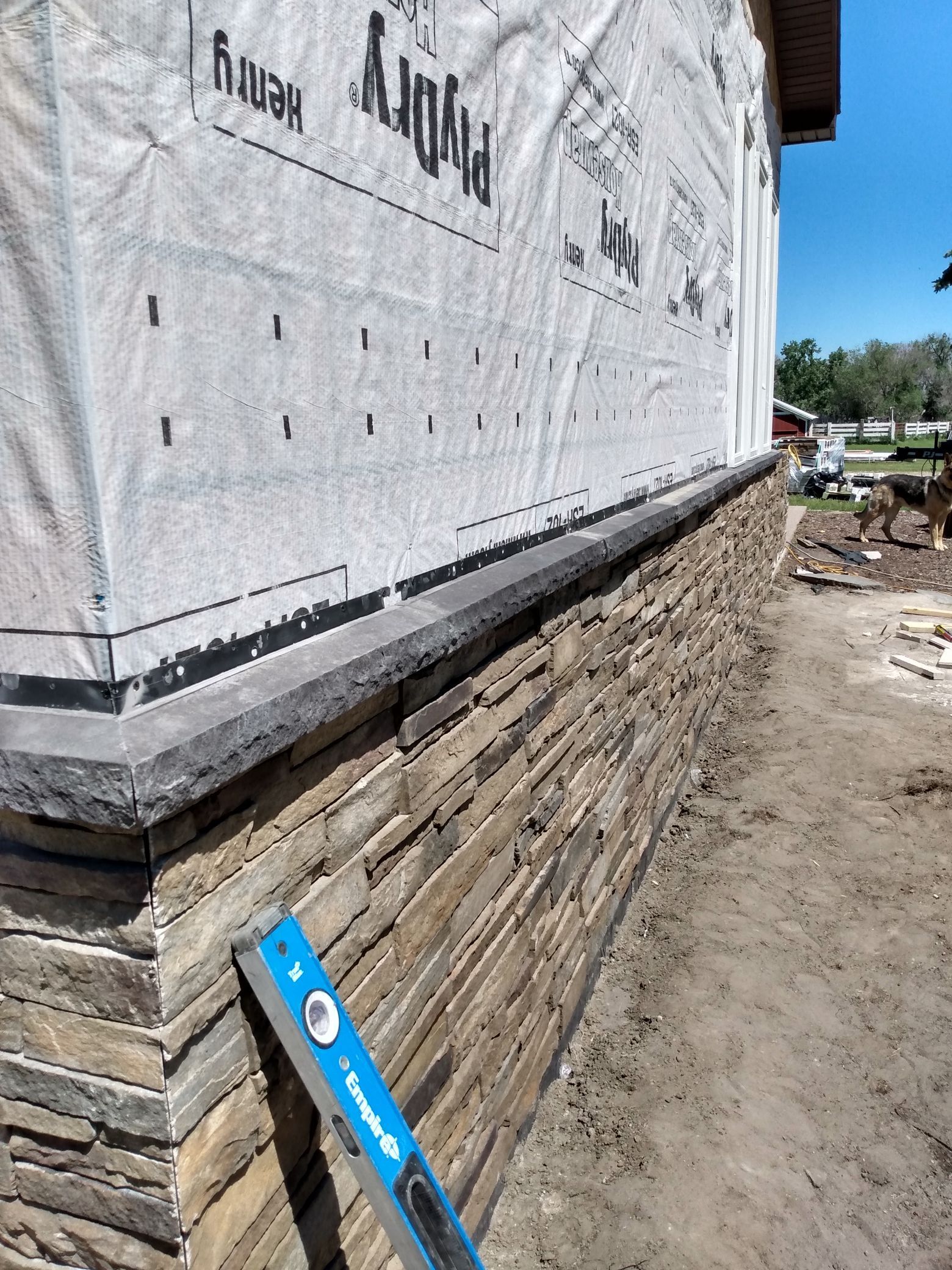 Partially built brick house with wrapped walls and a blue level leaning against the foundation