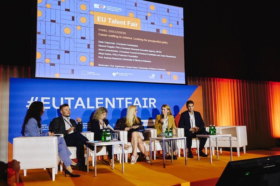 A group of people are sitting in front of a large screen at a conference.