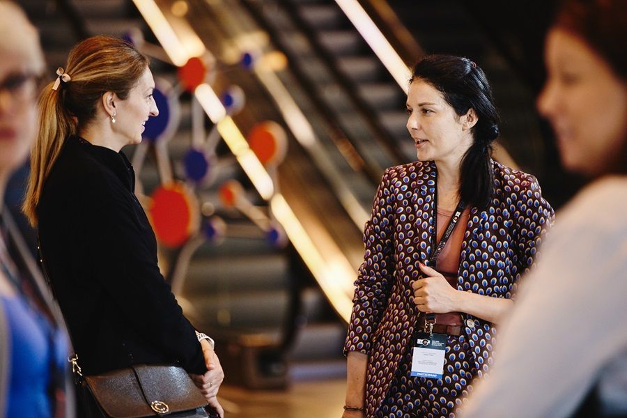 A group of women are standing next to each other and talking in front of an escalator.