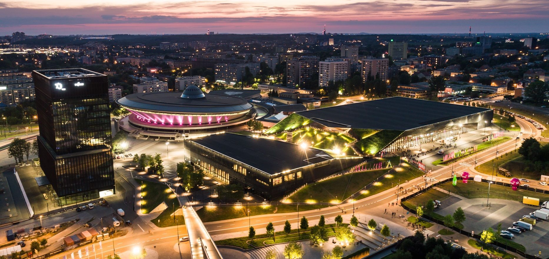An aerial view of a city at night with a large building in the middle of the city.