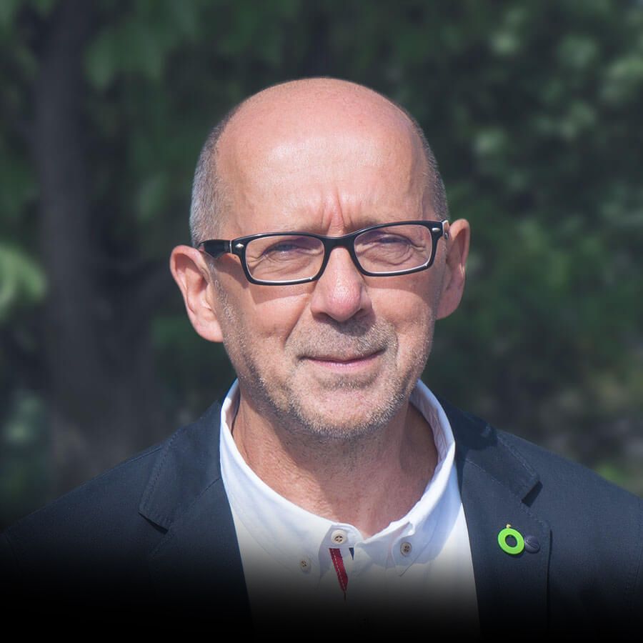 A bald man wearing glasses and a black jacket