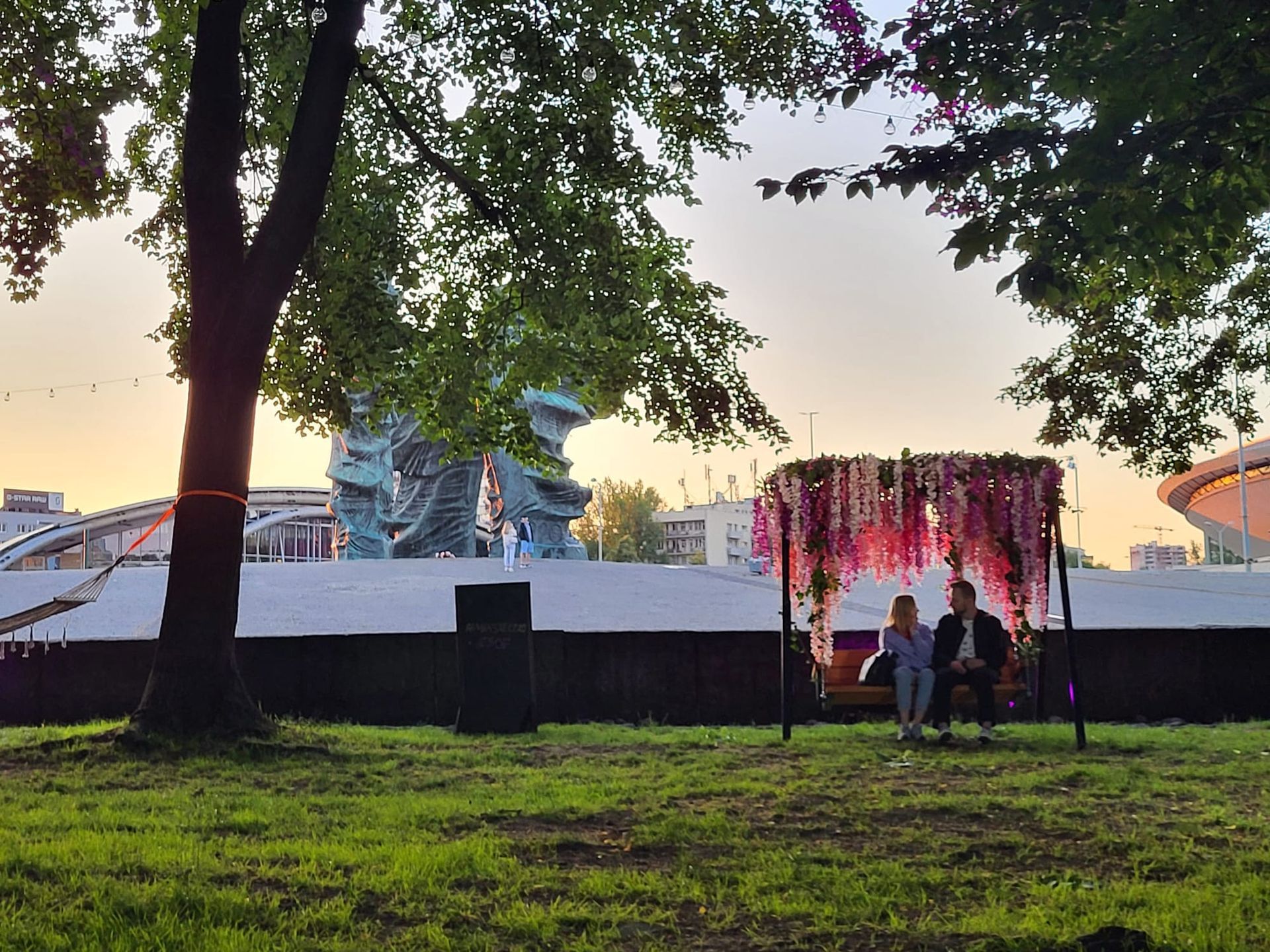 A man and a woman are sitting on a bench in a park.