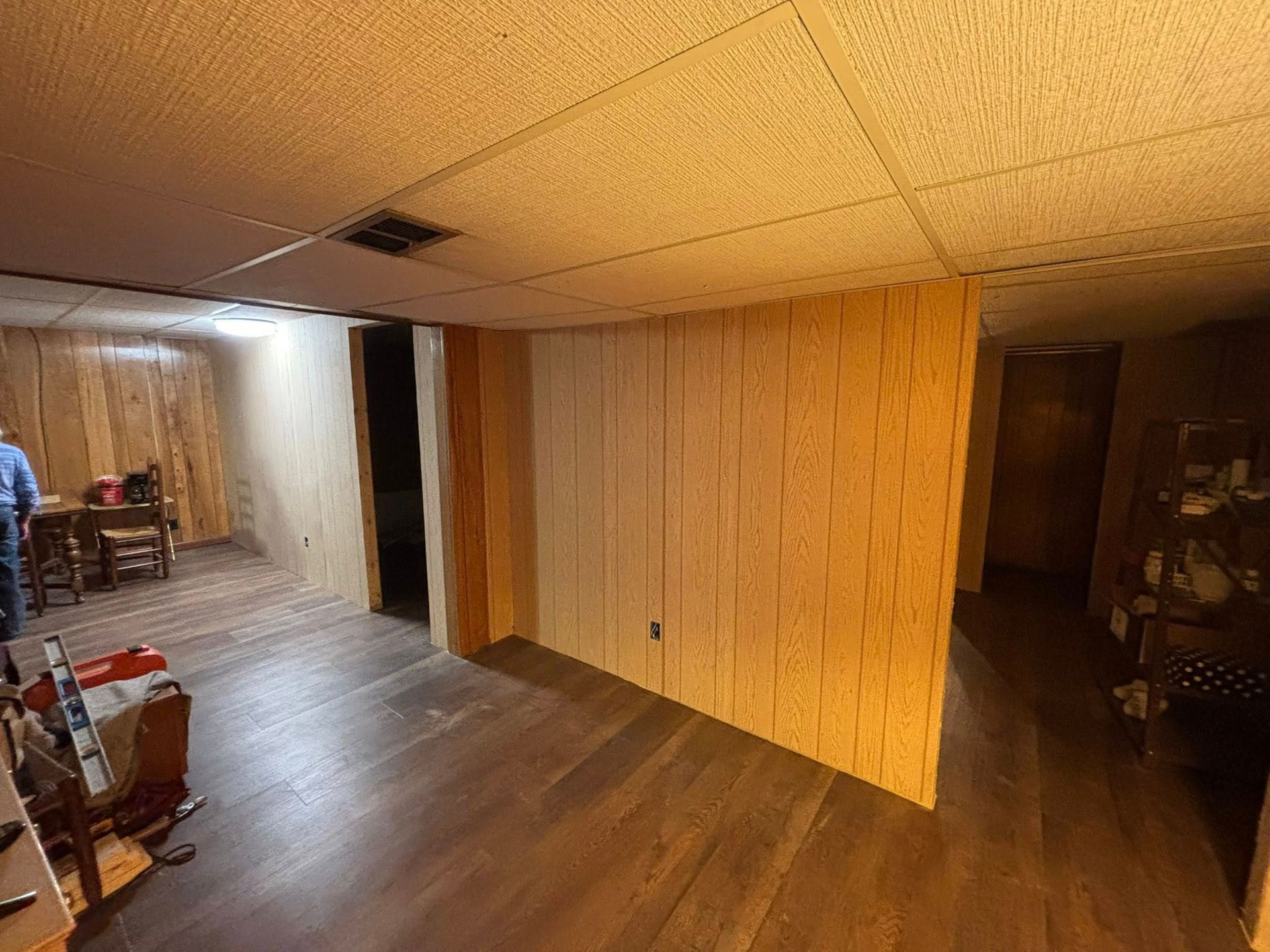 Basement room with wood paneling, carpet, and open doorway, lit by a ceiling light