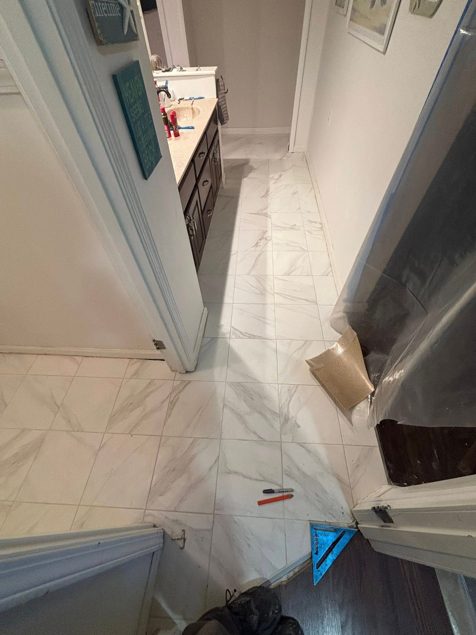 Narrow hallway with tiled floor, open doors, and a small debris pile near the right doorway.
