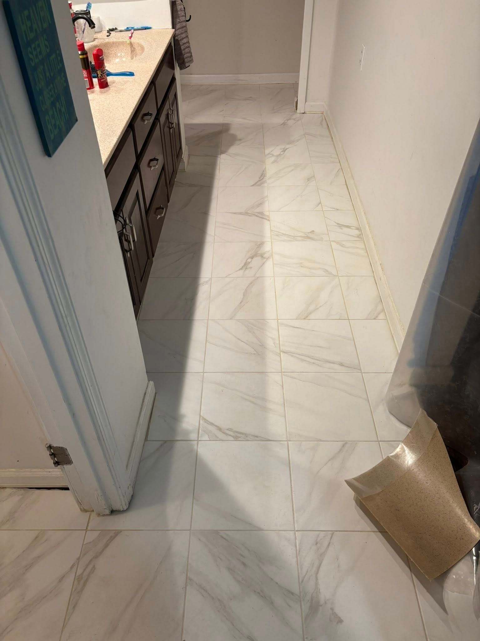 Hallway with white marble tile floor, open doorway, and a cardboard box on the right side.