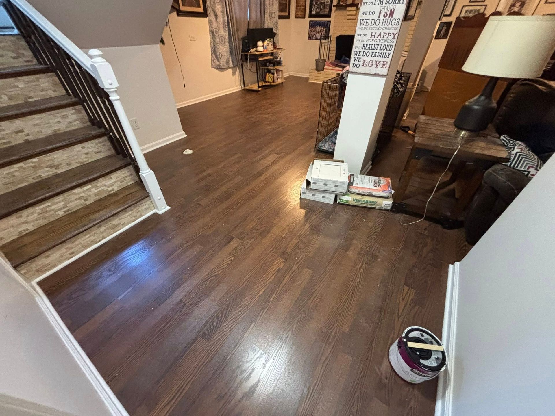 Living room with wood floors, staircase, lamp, and a pet bowl near the wall