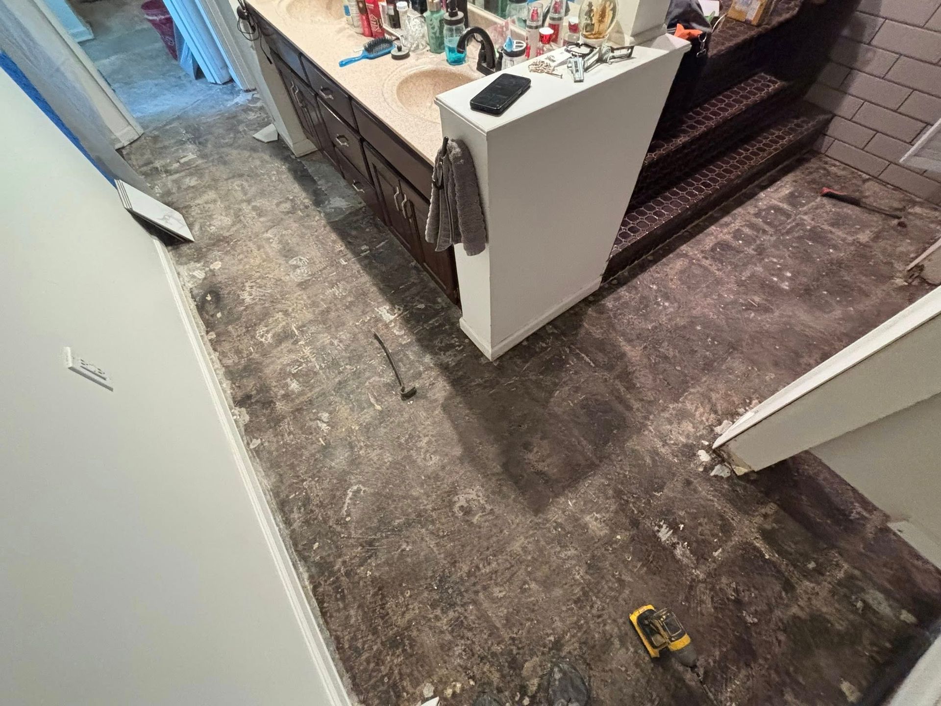 Partially renovated room with exposed floor, white cabinets, and tools scattered on the counter and floor